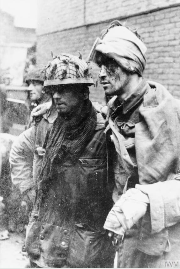 On This Day: 17th September 1944 THE BRITISH AIRBORNE DIVISION AT ARNHEM AND OOSTERBEEK IN HOLLAND  An Allied paratrooper assisting a wounded comrade. This photograph was taken at around 3.30pm east of the Arnhem main road bridge. From left to right. Sapper J Dunney, Sapper C Grier and Lance Corporal R Robb, all of the 1st Parachute Squadron, Royal Engineers. The men had just been shelled and burnt out of the van Lunburgstirum school which they had occupied since the evening of the 17 September. © IWM (HU 2131)